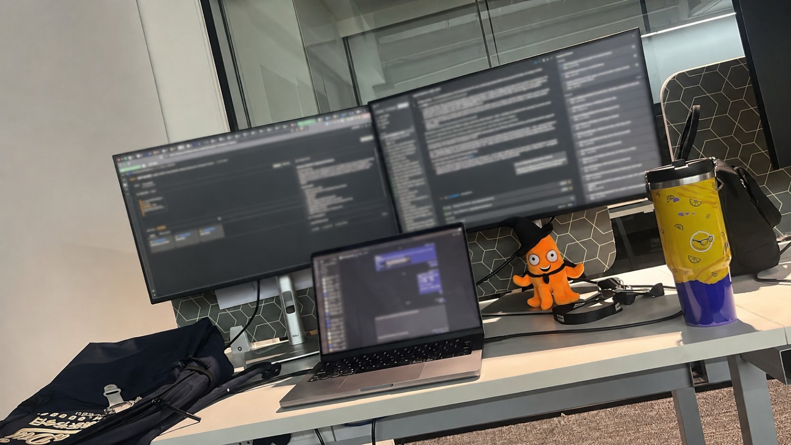 My desk: dual monitors and a laptop running code, with the orange Argo octopus mascot sitting under the monitors.