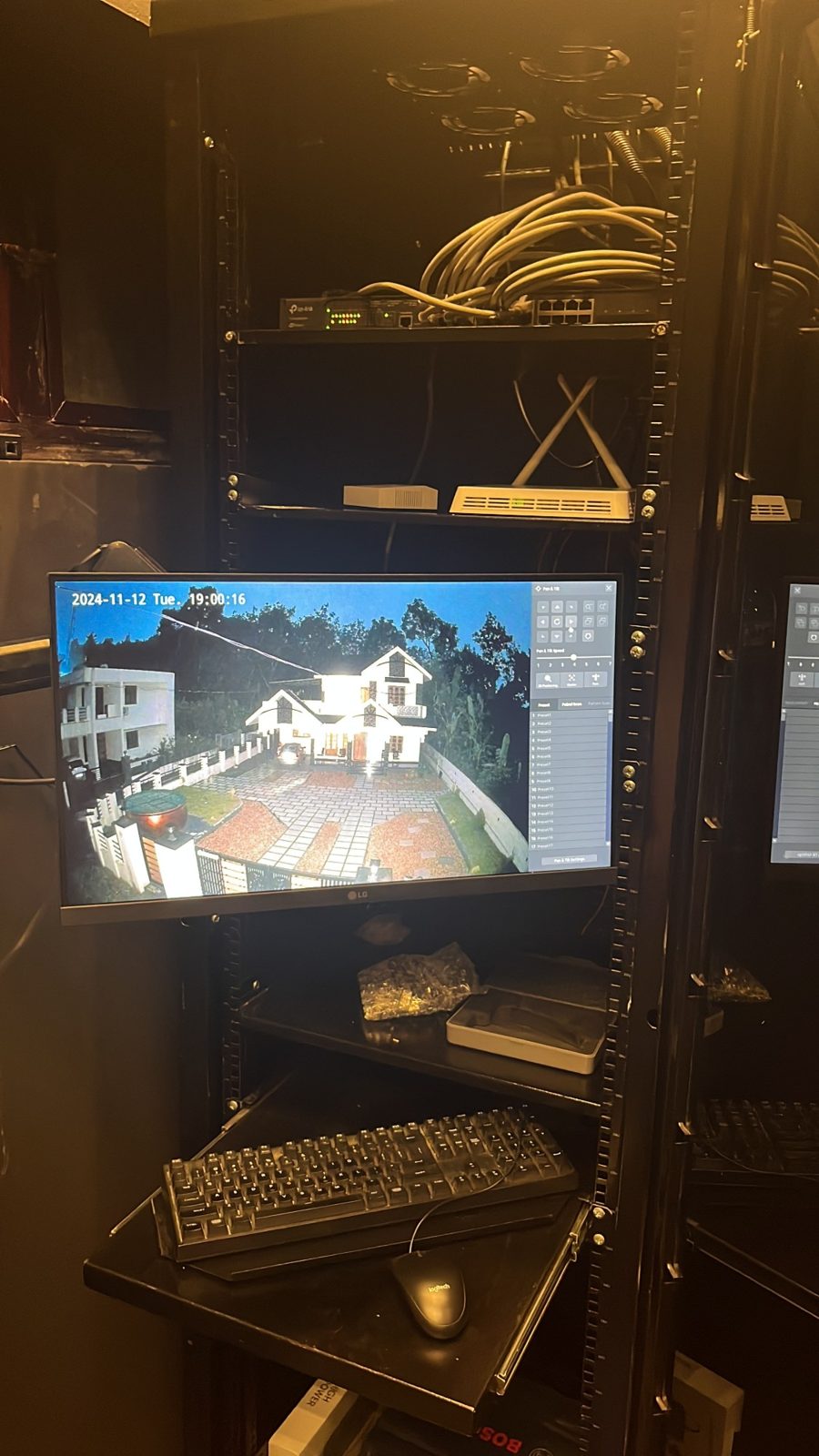 Inside the rack: the monitor showing a camera's pan-tilt view of the house, with the keyboard tray below