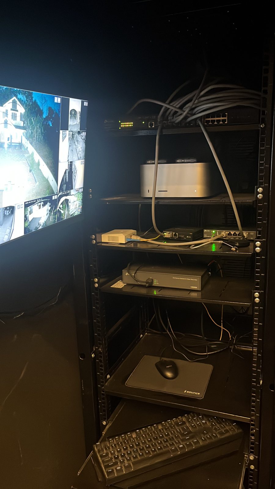 The finished rack: PoE switch, Mac Studio, OC200 controller, ER605 router, and NVR, with the camera wall visible