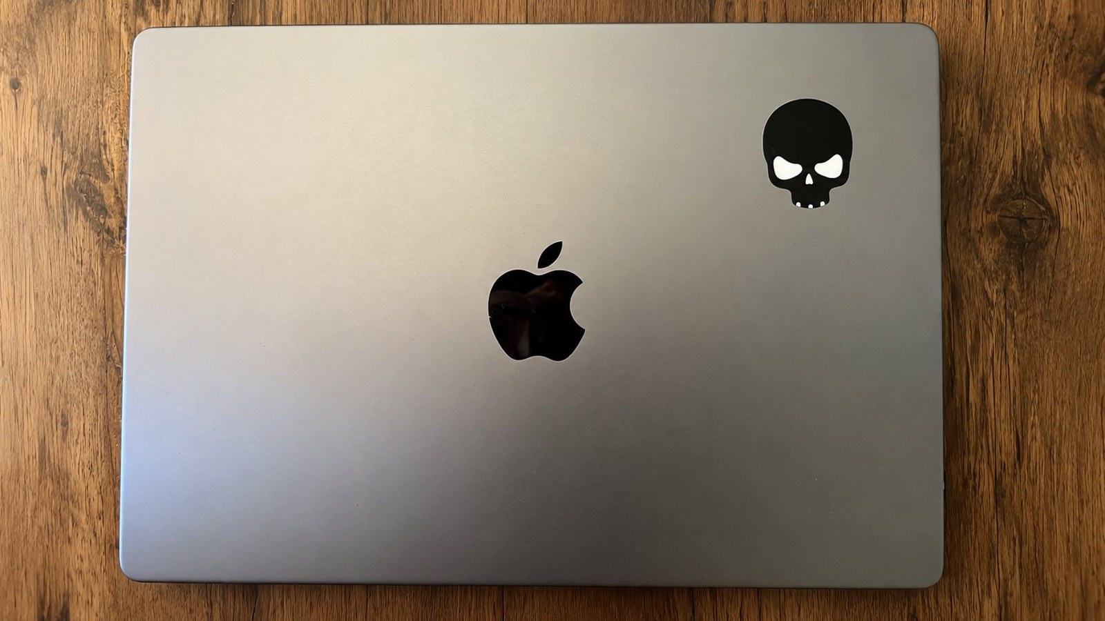 A MacBook lid with a single black skull sticker