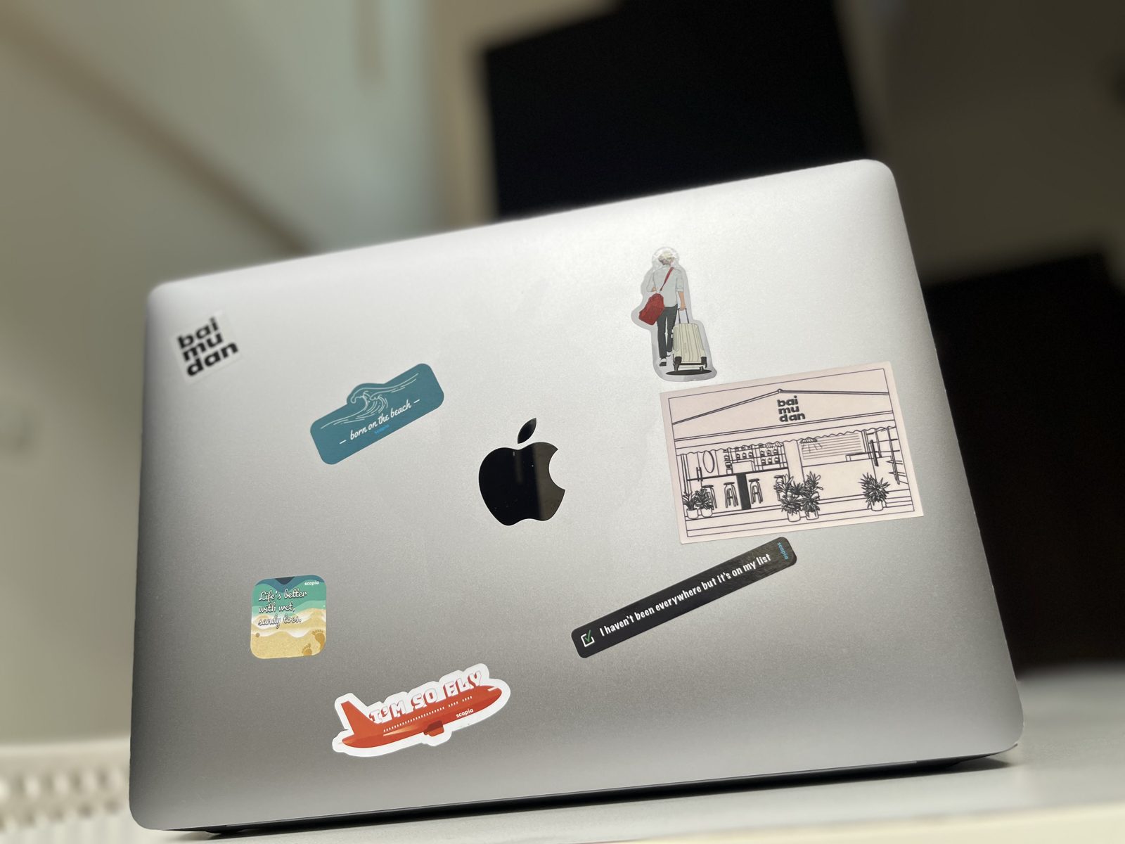 A MacBook lid with a small set of neatly spaced travel stickers